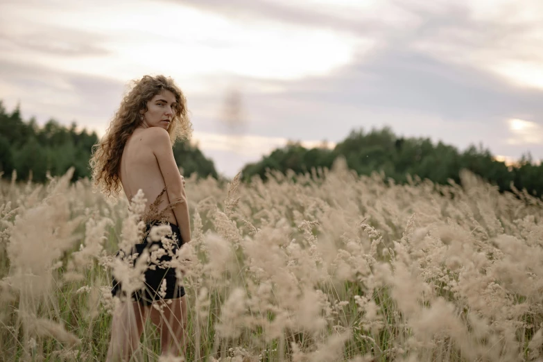 a woman standing in a field of tall grass, unsplash, renaissance, wearing a camisole and shorts, furr covering her chest, lorde, long grass in the foreground