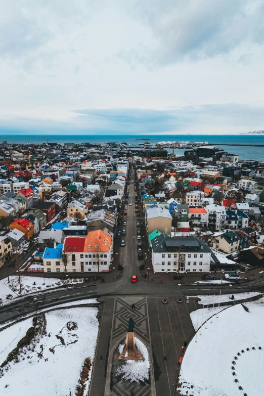 an aerial view of a city covered in snow, pexels contest winner, iceland hills in the background, various colors, square, seaside