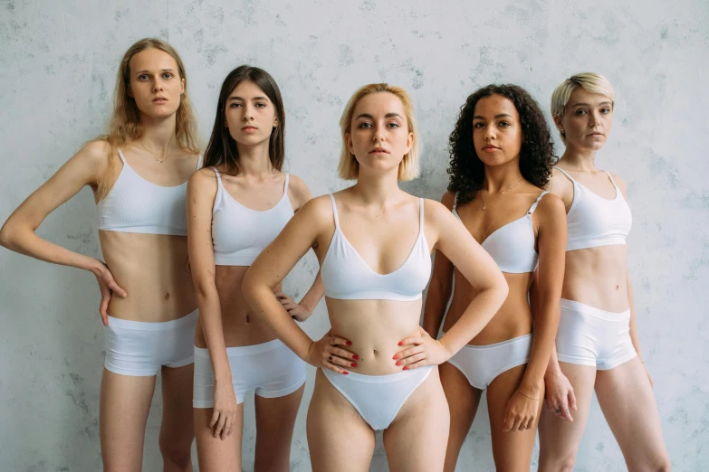 a group of women standing next to each other, inspired by Vanessa Beecroft, trending on pexels, antipodeans, wearing a white bikini, sport bra and shorts, fair skin, attractive girl