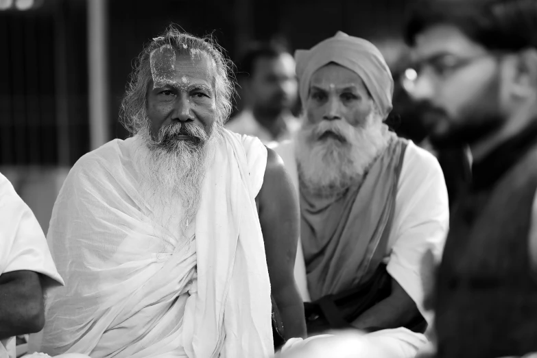 a group of men sitting next to each other, a black and white photo, by Bapu, pexels, samikshavad, long white hair and white beard, medium shot of two characters, at peace, speakers