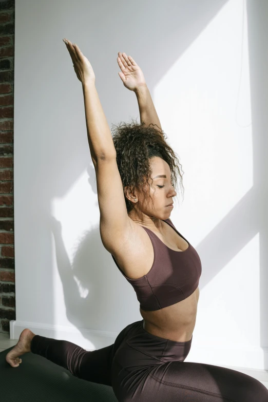 a woman doing a yoga pose in front of a window, by Carey Morris, trending on pexels, sports bra, african american woman, sun overhead, studio photo