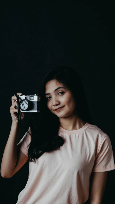 a woman taking a picture with a camera, by Basuki Abdullah, unsplash contest winner, on a gray background, slightly smiling, indoor picture, icon