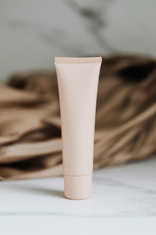 a tube of cream sitting on top of a counter, muted colored bodysuit, soft blush, matte photo, commercial banner