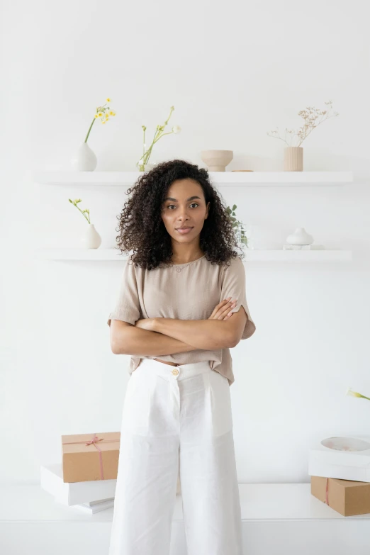 a woman standing in a white room with her arms crossed, inspired by Afewerk Tekle, standing on a shelf, wearing a linen shirt, customers, rj palmer