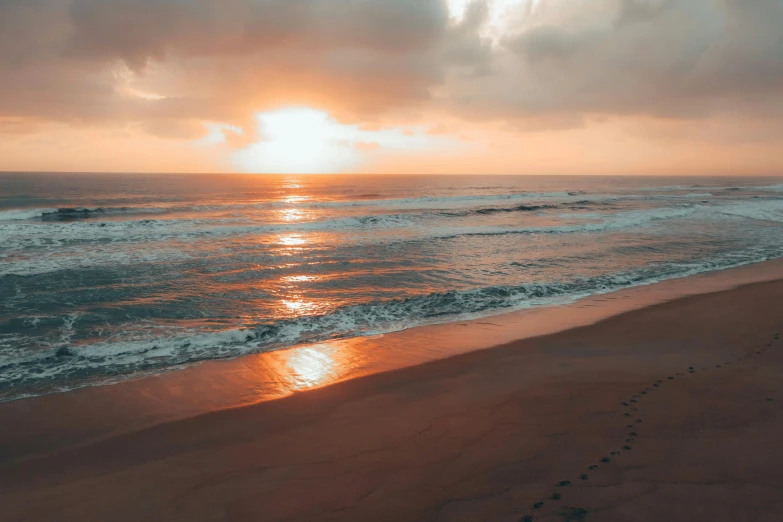 the sun is setting over the ocean on the beach, pexels contest winner, footprints, bali, instagram post, sunsetting color