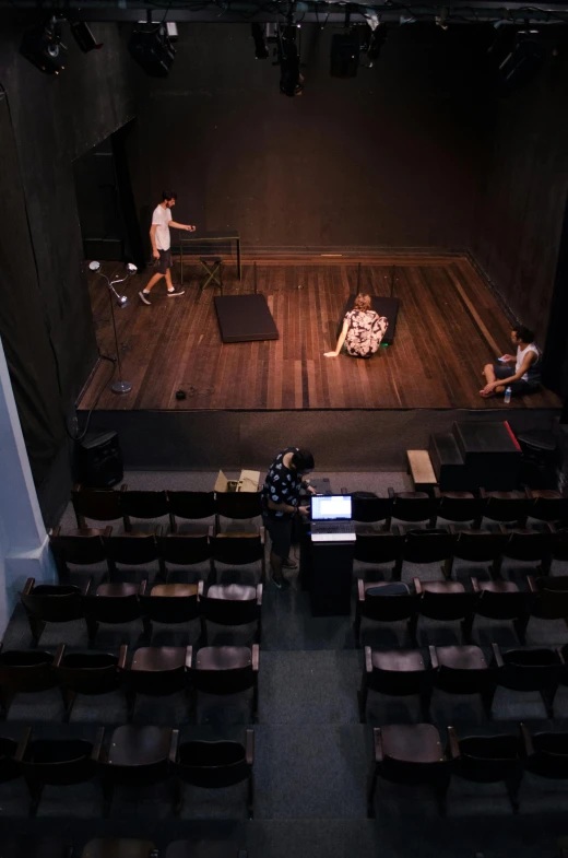 a group of people standing on top of a stage, by William Berra, happening, the backrooms are empty, photo taken from above, 3 actors on stage, looking sad