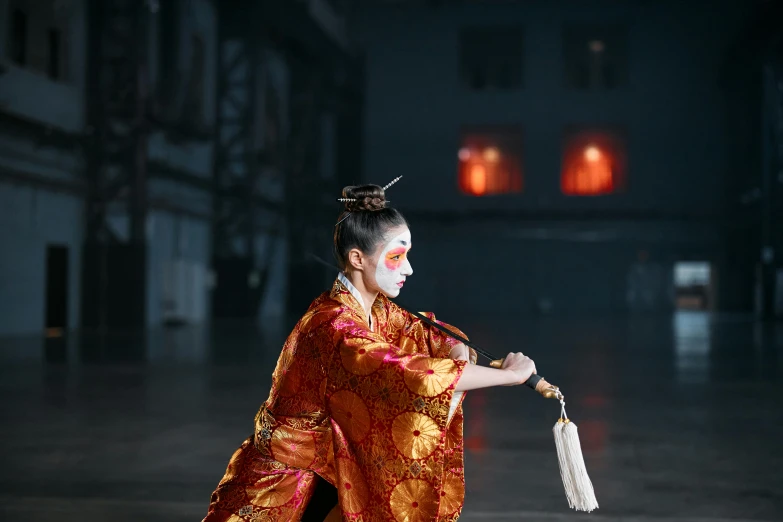 a woman in a red and gold outfit holding a fan, inspired by Kanō Hōgai, pexels contest winner, practising sword stances, woman in a dark factory, ( ( theatrical ) ), wearing silver silk robe