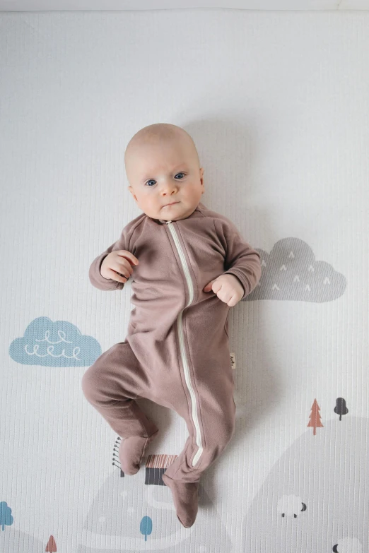 a baby is hanging upside down on a wall, a cartoon, unsplash, brown clothes, pink and grey clouds, official product photo, catsuit