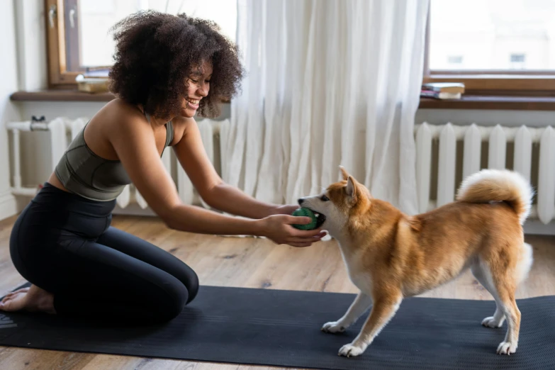 a woman playing with a dog on a yoga mat, tapping in to something greater, manuka, very excited, with abs