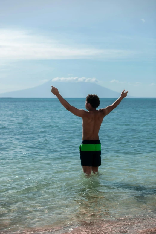 a man standing in the water with his arms outstretched, happening, island in the background, indonesia, slide show, cheering