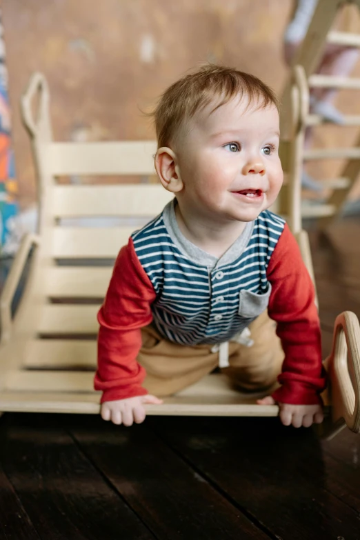 a baby is playing with a wooden toy, by Sven Erixson, unsplash, sitting in a rocking chair, softplay, running towards camera, striped