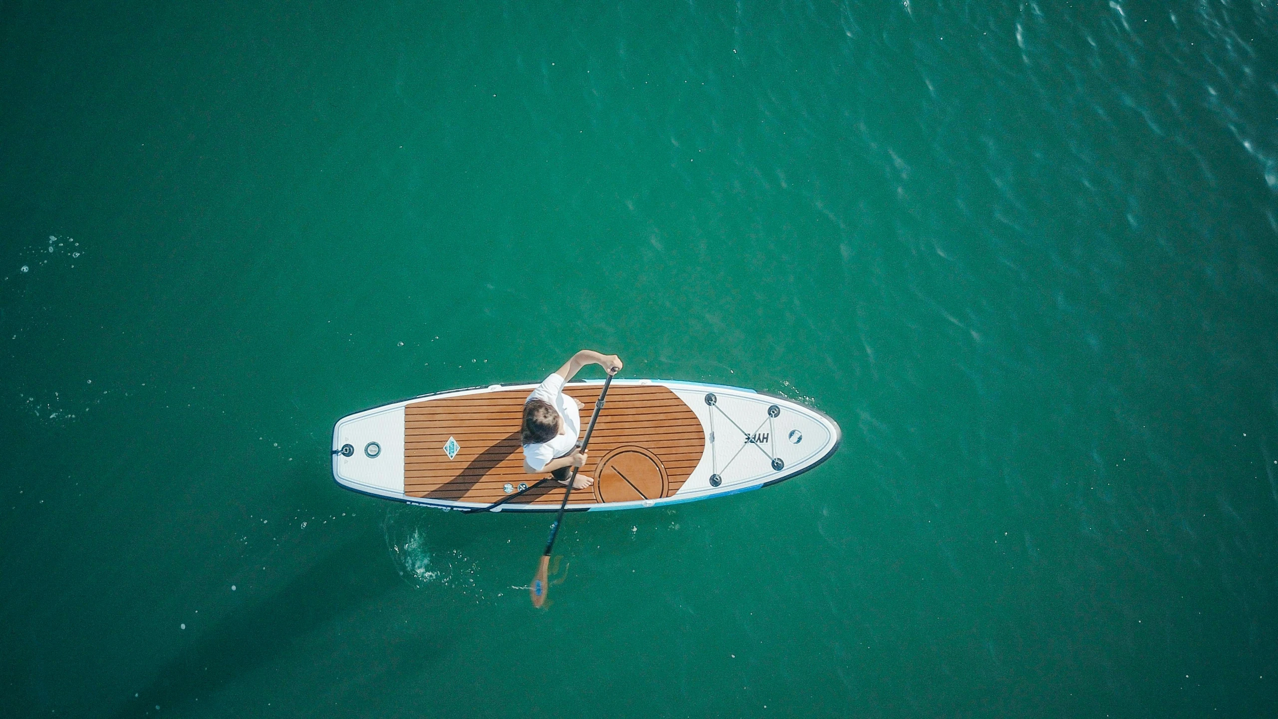 a man riding a paddle board on top of a body of water, view from the sky, manly, thumbnail, guide