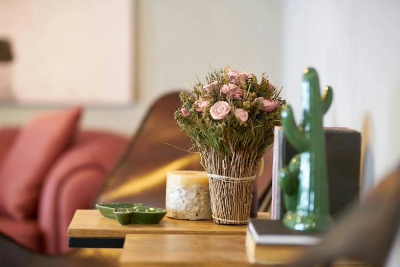 a wooden table topped with a vase filled with flowers, inspired by Alexander Roslin, romanticism, pink rosa, dried flower, with cactus plants in the room, product display photograph