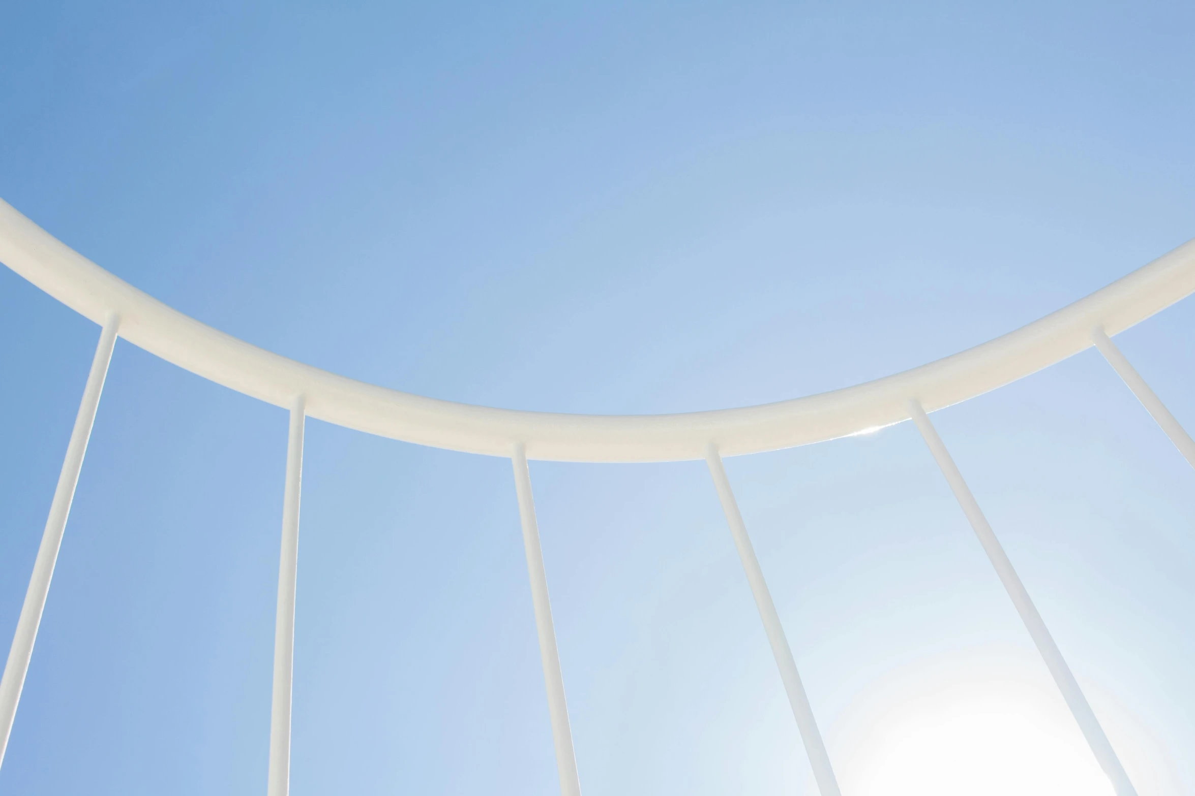 a man flying through the air while riding a skateboard, an abstract sculpture, inspired by Lucio Fontana, unsplash, minimalism, sky bridge, white and pale blue, circular, sun shining