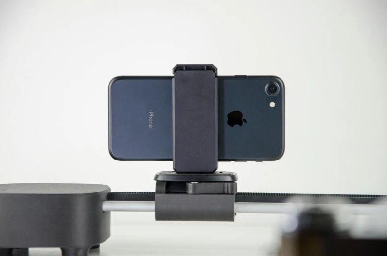 a couple of cell phones sitting on top of a table, a picture, posing for a picture, 3d printed, mount, all black matte product