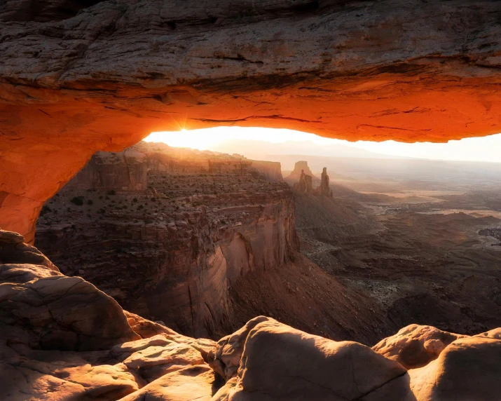 the sun shines through an arch in the desert, pexels contest winner, hudson river school, buildings carved out of stone, cave lighting, red cloud light, view out of a window