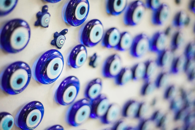 a wall with a lot of evil eyes on it, a mosaic, by Micha Klein, pexels, displayed on an altar, dipped in polished blue ceramic, eye implants, hand