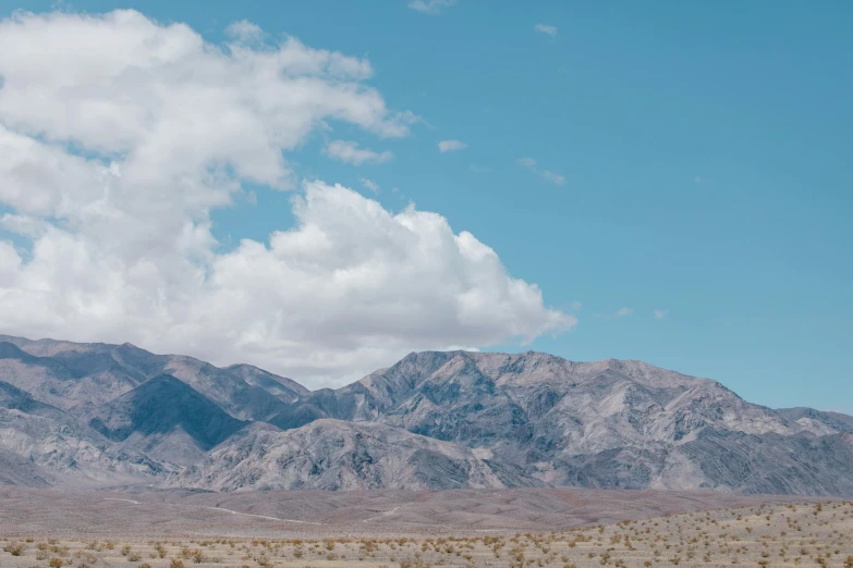 a stop sign in the middle of a desert with mountains in the background, unsplash contest winner, background image, large white clouds, palm springs, panoramic shot