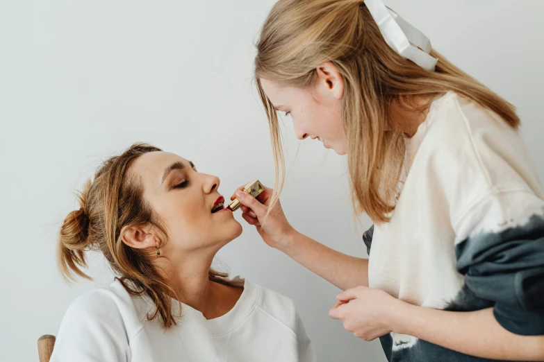 a woman brushing another woman's teeth with a brush, by Lee Loughridge, trending on pexels, straya, wearing professional makeup, frank moth, on a white table