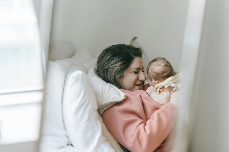 a woman laying in bed holding a baby, pexels contest winner, avatar image, 1 2 9 7, small, cinematic image