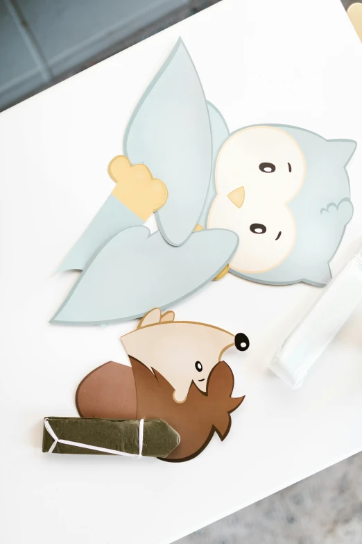 a close up of a piece of paper with stickers on it, a cartoon, by karlkka, barn owl mask, light grey blue and golden, hibernation capsule close-up, lying down