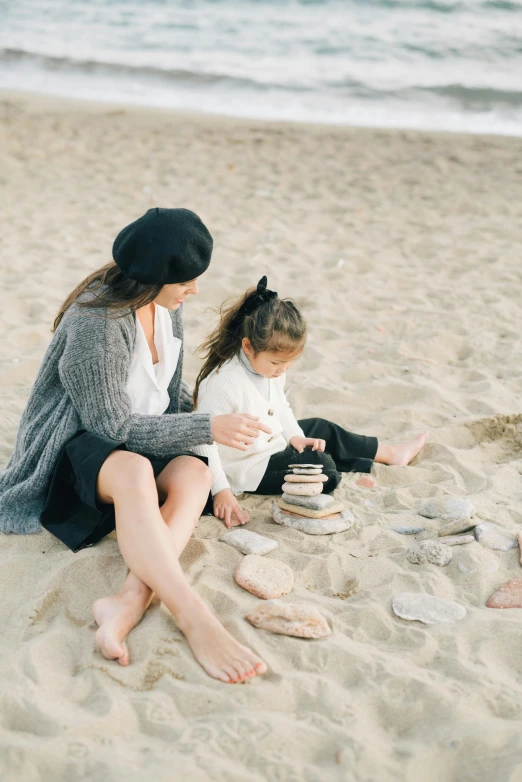 a woman sitting on top of a sandy beach next to a child, flatlay, hygge, profile image, dwell