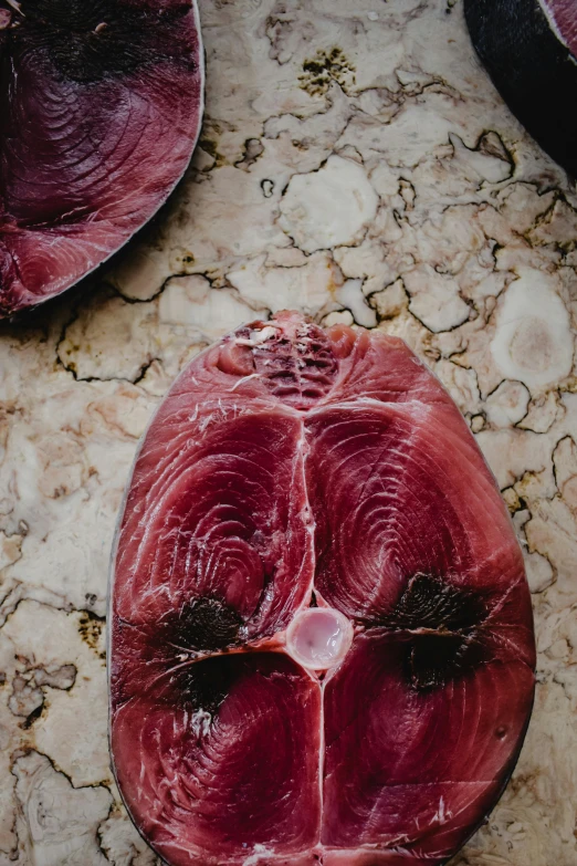 a close up of a piece of meat on a table, maroon, dead fish, magnificent oval face, flatlay