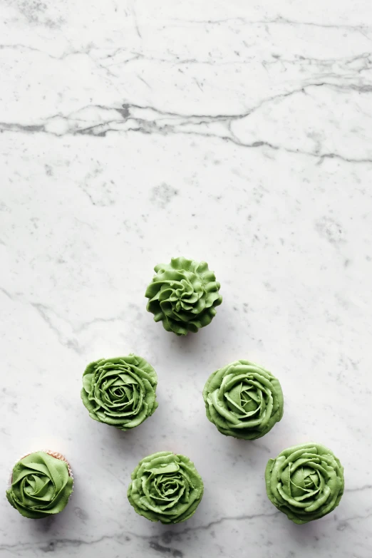 a table topped with cupcakes covered in green frosting, a picture, inspired by Art Green, trending on pexels, made of carrara marble, artichoke, uncrop, 6 k