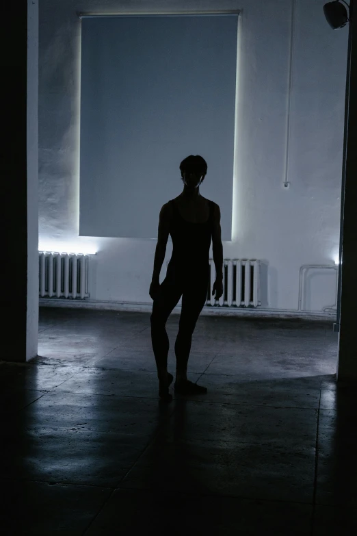 a silhouette of a man standing in a dark room, inspired by Bruce Nauman, light and space, female dancer, looking sad, ignant, taken in the late 2010s