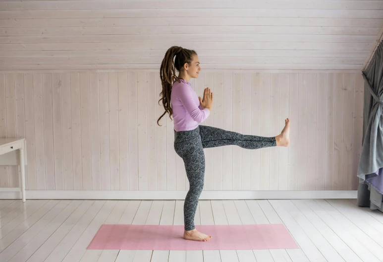 a woman doing a yoga pose on a pink mat, arabesque, standing, no cropping, sarah cliff, leg high