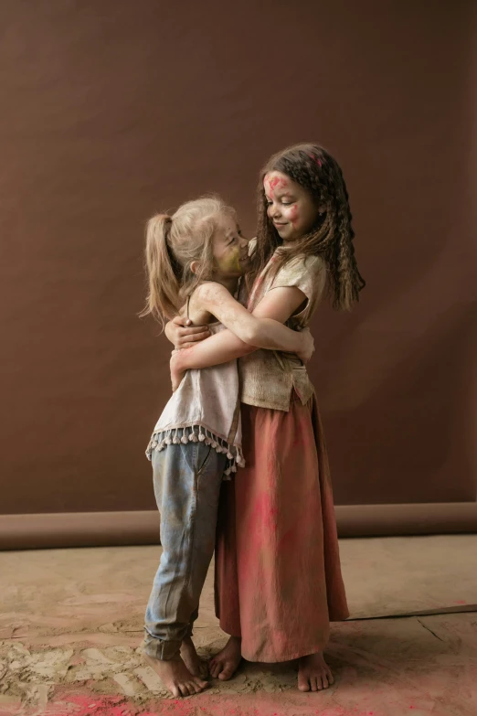 a couple of little girls standing next to each other, a picture, inspired by Frieke Janssens, shutterstock contest winner, antipodeans, covered in dust, neanderthal people, hugging each other, brown colours