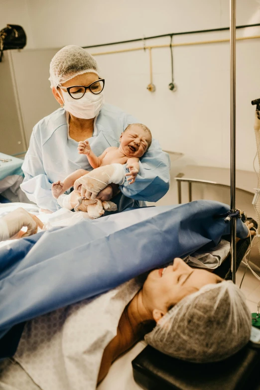 a man laying in a hospital bed holding a baby, pexels contest winner, happening, surgical gown and scrubs on, animals, exploded belly, gif