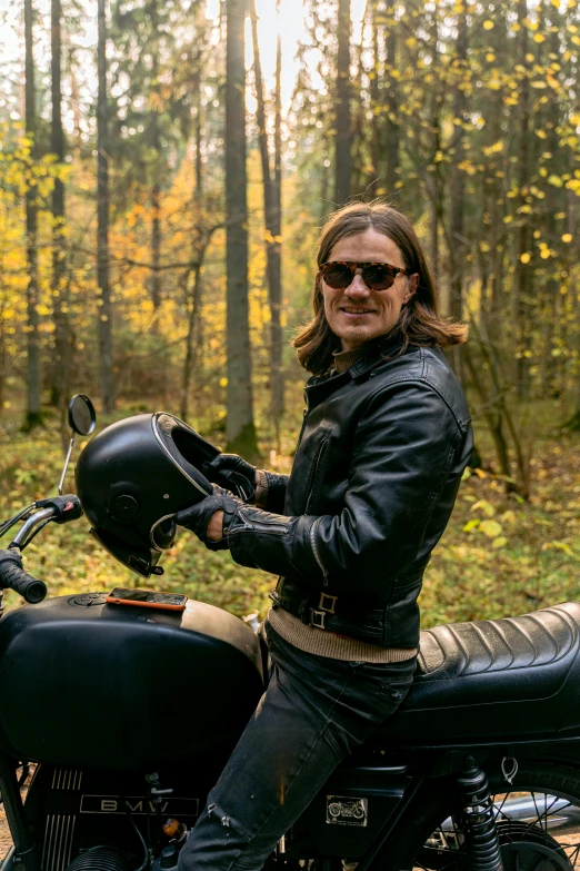 a man sitting on a motorcycle in the woods, adam driver, wearing oakley sunglasses, sweden, profile image