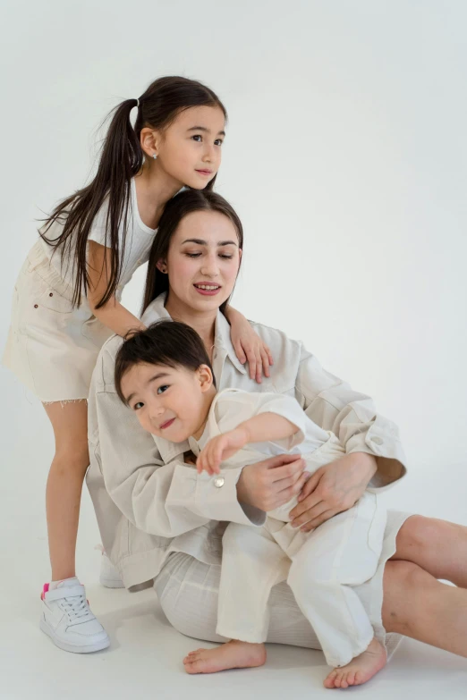 a woman and two children posing for a picture, inspired by Louis Le Nain, pexels contest winner, incoherents, wearing off - white style, hana alisa omer, plain background, promotional image