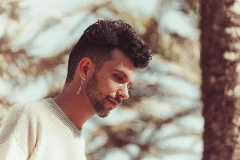 a man standing next to a tree using a cell phone, an album cover, pexels contest winner, a handsome man，black short hair, profile image, miguel angel, on a pale background