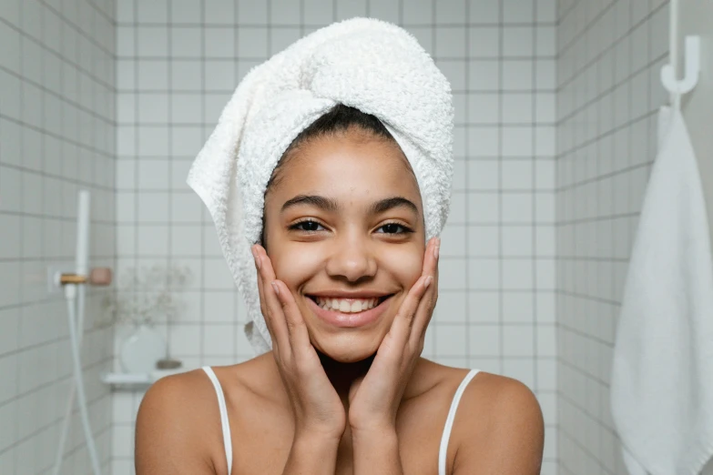 a close up of a person with a towel on their head, with a beautifull smile, brown skinned, wide forehead, hands on face