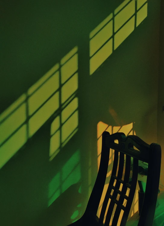 a wooden bench sitting in front of a window, an album cover, inspired by Joseph Wright of Derby, unsplash, sickly green colors, shadows. asian landscape, sitting in a chair, green and yellow
