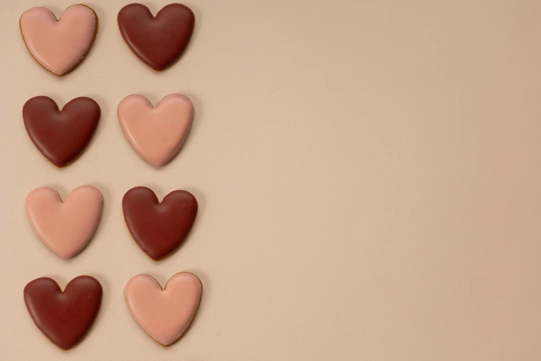 a group of heart shaped cookies sitting on top of a table, by Emma Andijewska, trending on pexels, brown and pink color scheme, background image, minimalistic art, brown