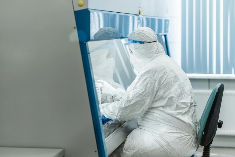 a person in a white suit sitting at a desk, staff wearing hazmat suits, avatar image, maintenance photo, surgical supplies