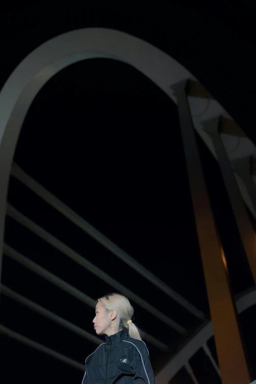 a man standing on top of a bridge at night, by Steve Brodner, happening, lady gaga as evita, dramatic press photo, tall arches, concerned expression