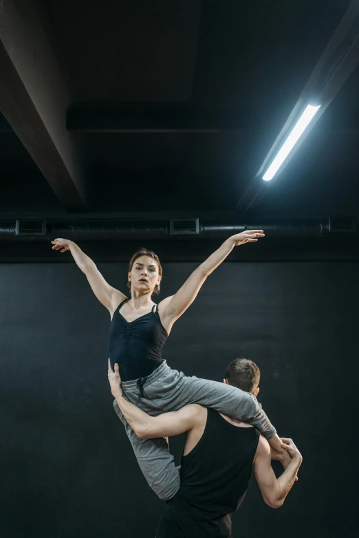 a man and a woman in a black leo leo leo leo leo leo leo leo leo leo, by Elizabeth Polunin, unsplash, arabesque, hanging from the ceiling, sydney hanson, in a jumping float pose, non-binary