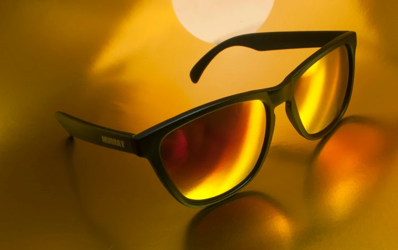 a pair of sunglasses sitting on top of a table, by James Warhola, colors: yellow, dramatic lighting - n 9, dynamic closeup, hansa yellow