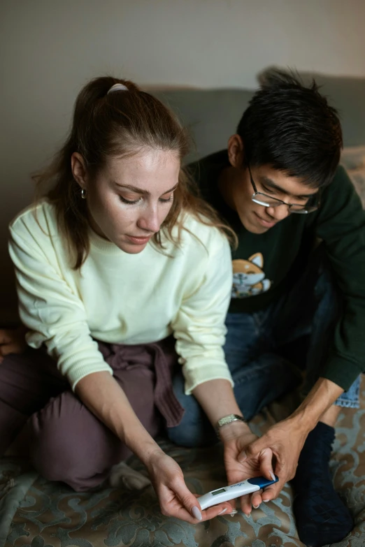 a man and a woman sitting on a bed looking at a cell phone, holding paws, college students, lee madgwick & liam wong, supportive