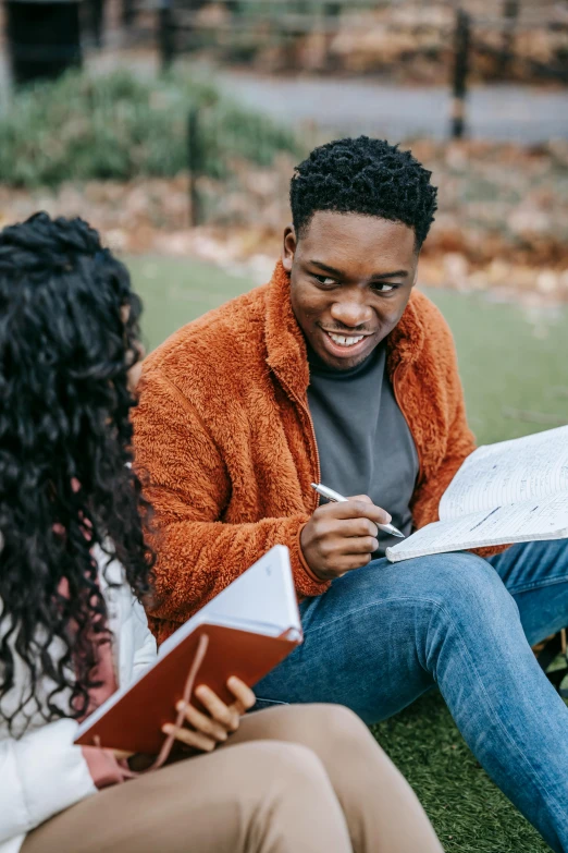 a couple of people that are sitting in the grass, trending on pexels, academic art, black man, charts, holding books, autumnal