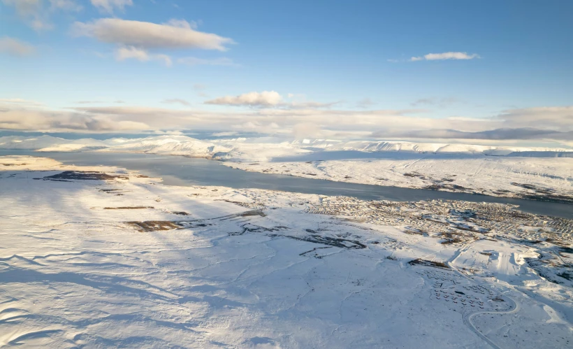 a man riding skis on top of a snow covered slope, by Hallsteinn Sigurðsson, hurufiyya, aerial view of a city, an island floating in the air, nina tryggvadottir, snow capped mountains