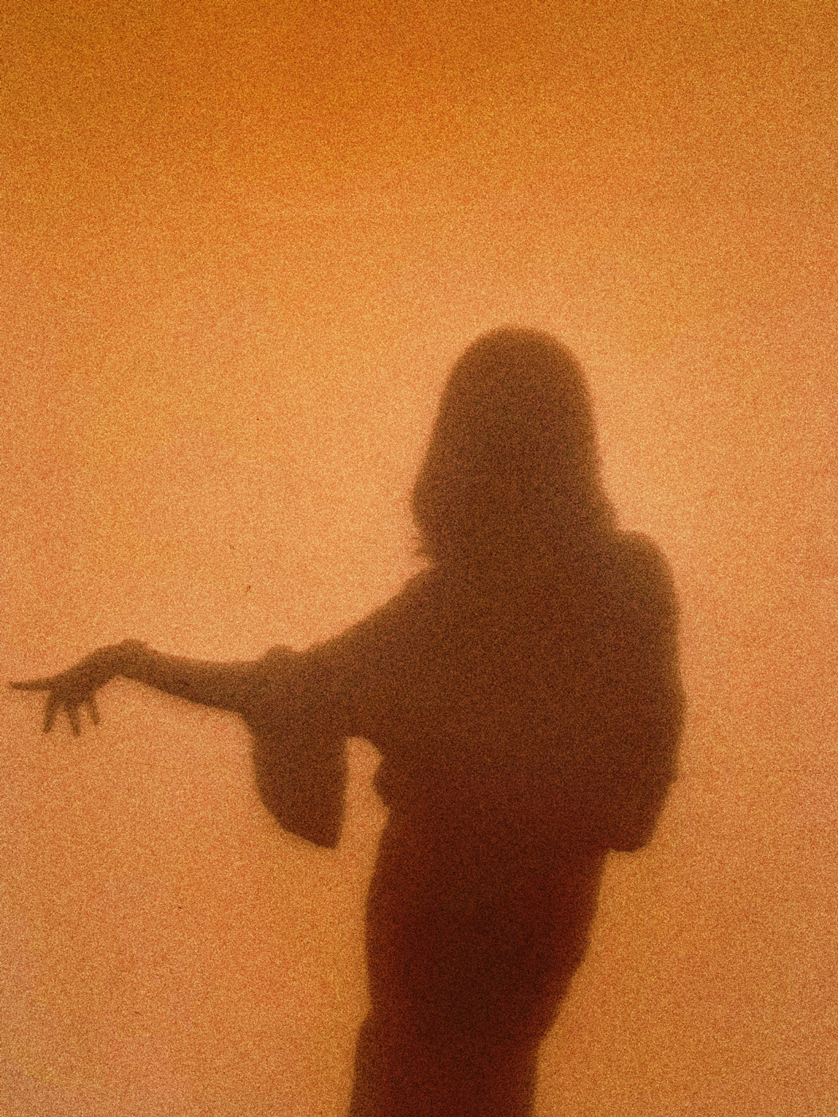 a silhouette of a woman standing in front of a wall, an album cover, inspired by Elsa Bleda, unsplash, surrealism, orange fog, forming a burning hand spell, 1 9 7 0 s analog aesthetic, scary shadow people