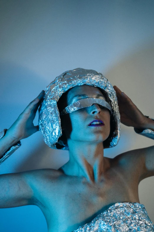 a woman in a silver dress posing for a picture, inspired by Cindy Sherman, unsplash, holography, wearing her helmet, covered in bandages, halo above head, non binary model