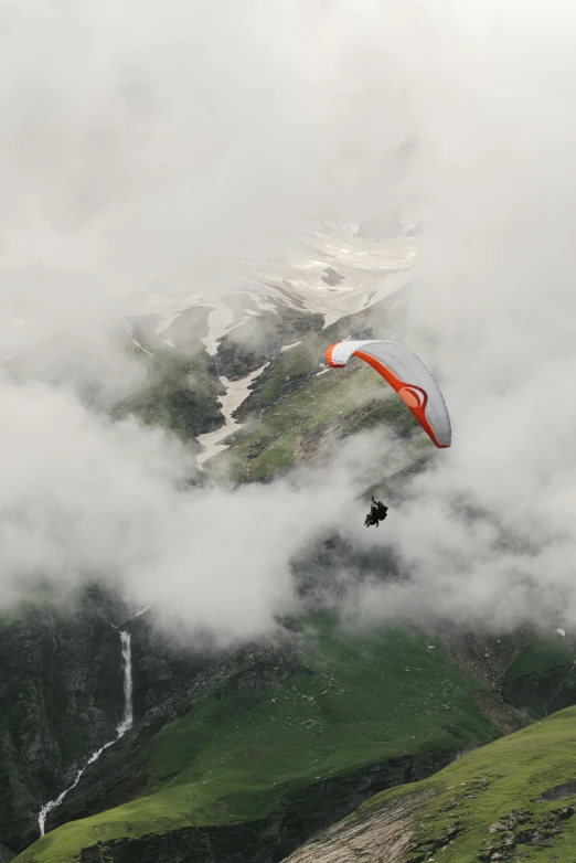 a person paragliding in the mountains on a cloudy day, by Daren Bader, high view, high polygon, no crop, cinematic