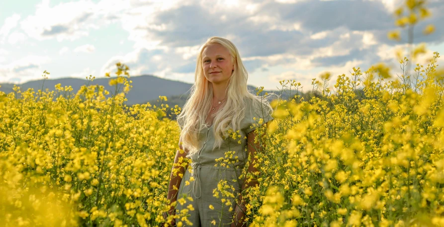 a woman standing in a field of yellow flowers, a portrait, by Else Alfelt, pexels contest winner, greta thunberg, light yellow hair, farmer, full body image