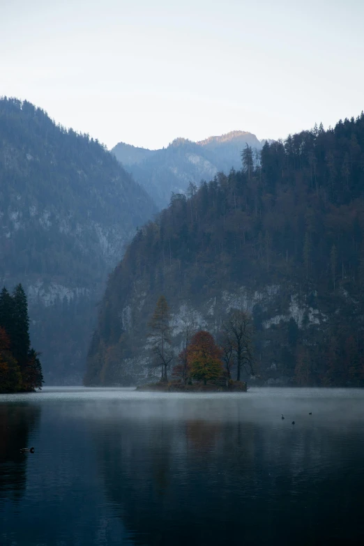 a body of water with mountains in the background, slovenian, muted fall colors, february)